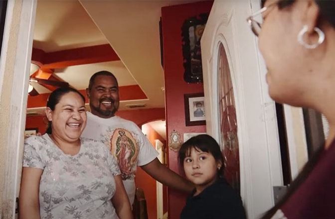 Three residents of a Colonias community greet a visitor at their door.